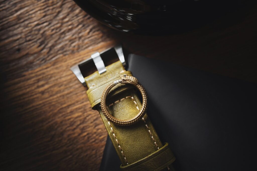 a watch sitting on top of a table next to a bottle of wine